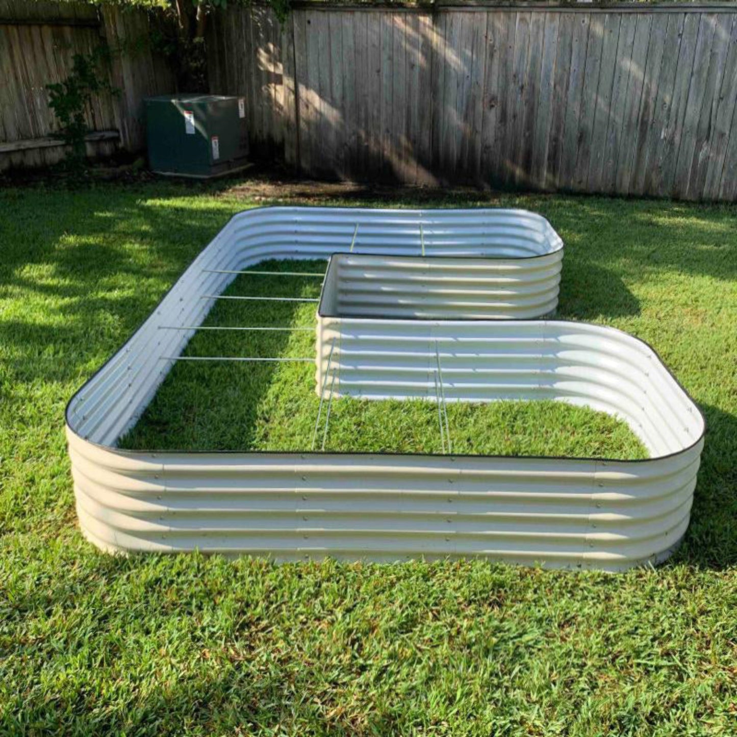 Image of the pearl white U-shaped metal raised garden bed jumbo sized sitting empty on the grass in a backyard.