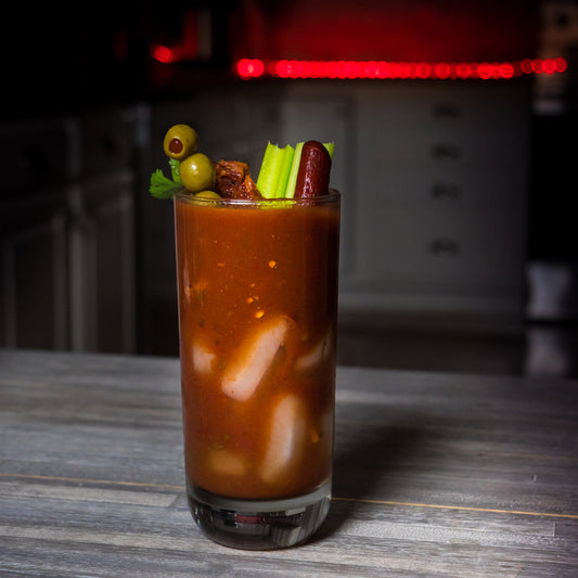Spicy Bloody Mary cocktail garnished with olives, celery, and pepperoni stick, made with Carolina Reaper mash for extreme heat