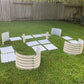 Image of the pearl white U-shaped metal raised garden bed disassembled on the grass in a backyard.