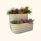 A pearl white  cascading metal Garden Bed with colorful flowers and plants on a white background.