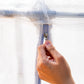 Hand zipping a the mesh cover system for raised garden beds in a close up image.