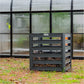 Modular Compost bin in front of a greenhouse in a backyard setting.