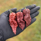 Pepper Joe's Chocolate Ghost Pepper Pods. Three mature peppers shown to represent seeds for sale, held in a black gloved hand