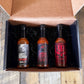 Pepper Joe's Tour of Heat hot sauce gift box that includes one bottle each of Ghost Pepper, XXX Habanero, and Carolina Reaper packaged inside gift box on a rustic background.