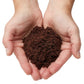 Hands holding hydrated Urban Worm Coco Coir on a white background
