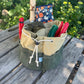 Green tool roll with gardening tools on a wooden surface with greenery in the background