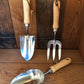 Set of three garden tools with wooden handles on a wooden surface