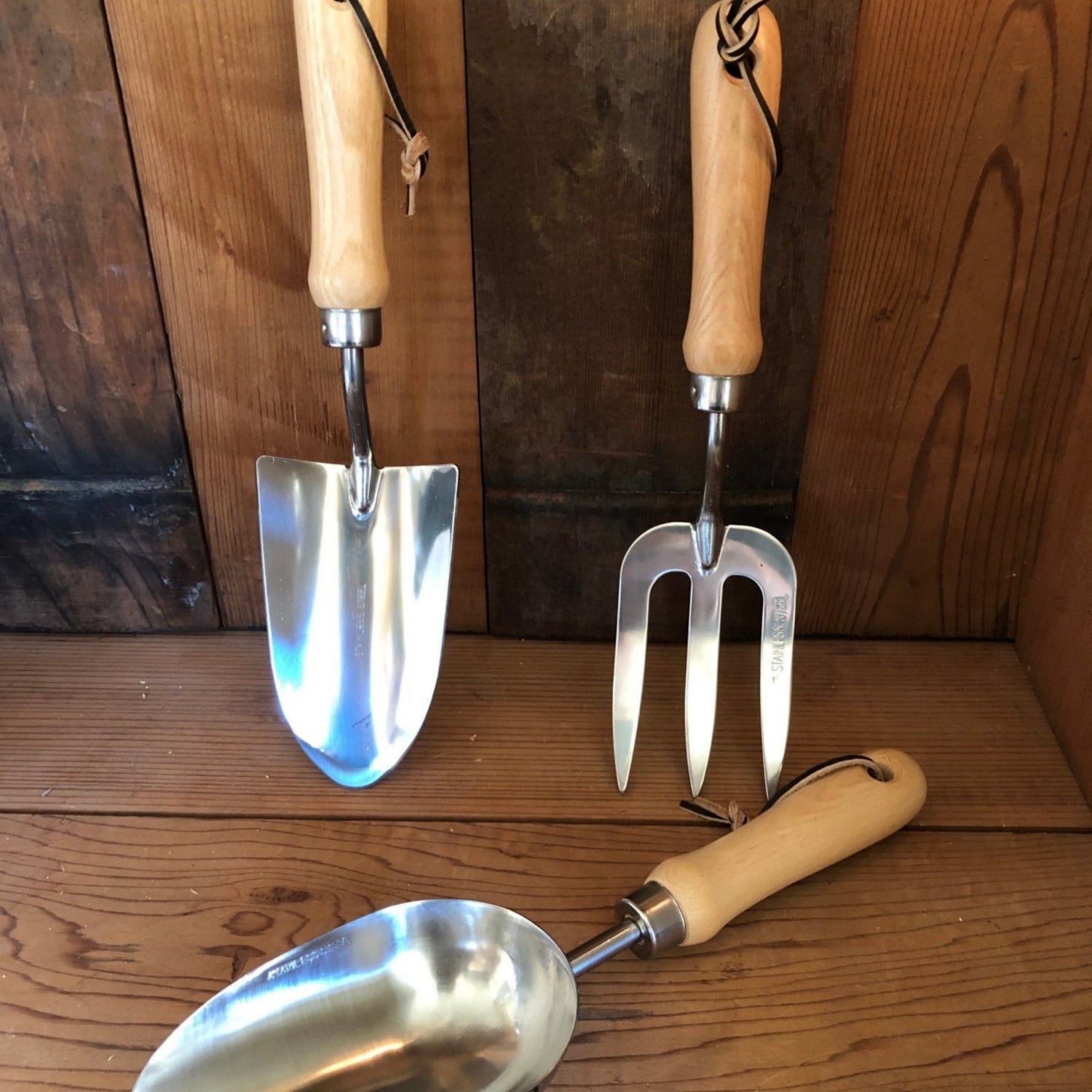 Set of three garden tools with wooden handles on a wooden surface