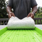 Person holding hemp grow mat above green seed tray showing underside of soilless growing medium used for hydroponics and microgreens